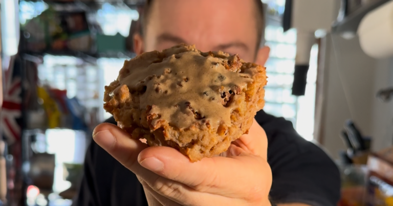 One of the high protein baked apple fritters with streusel and vanilla frosting held toward the camera